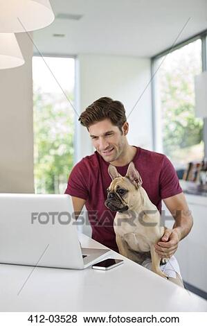 Man using laptop with dog on lap View Large Photo Image Stock Photo - Man using laptop with dog on lap. Fotosearch