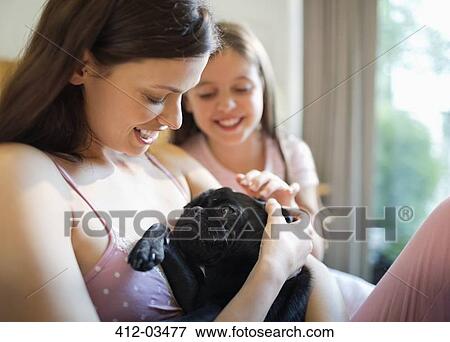 Mother and daughter petting dog in bed View Large Photo Image Stock Photo - Mother and daughter petting dog in bed. Fotosearch