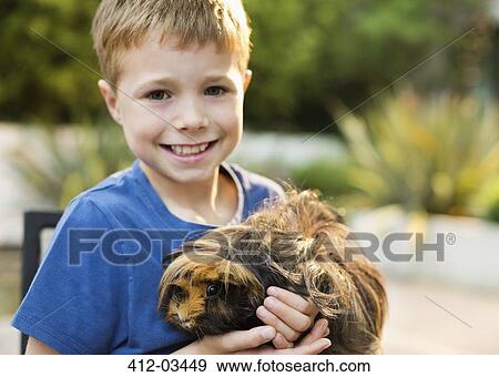 Smiling boy holding guinea pig outdoors View Large Photo Image Stock Photo - Smiling boy holding guinea pig outdoors. Fotosearch