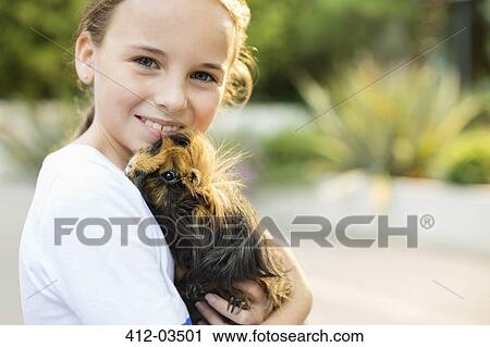 Smiling girl holding guinea pig outdoors View Large Photo Image Stock Image - Smiling girl holding guinea pig outdoors. Fotosearch