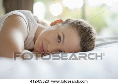 Stock Image - Smiling girl laying on bed. Fotosearch