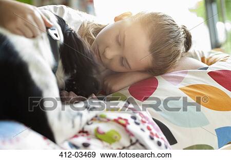 Smiling girl petting dog in bed View Large Photo Image Stock Photo - Smiling girl petting dog in bed. Fotosearch