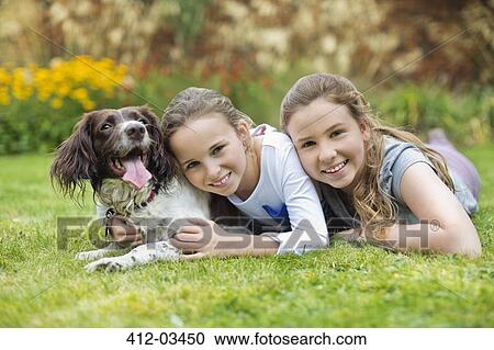 Smiling girls relaxing with dog on lawn View Large Photo Image Stock Image - Smiling girls relaxing with dog on lawn. Fotosearch