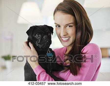 Smiling woman holding dog indoors View Large Photo Image Stock Photo - Smiling woman holding dog indoors. Fotosearch