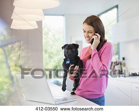 Woman on cell phone holding dog View Large Photo Image Stock Image - Woman on cell phone holding dog. Fotosearch