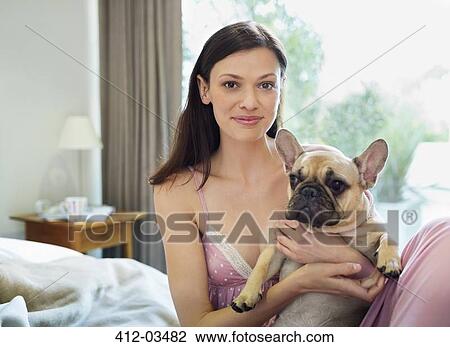 Stock Image - Woman petting dog in bed. Fotosearch