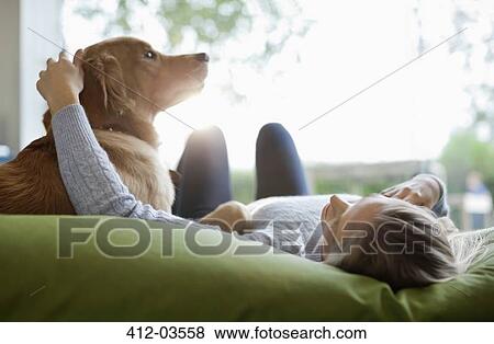 Stock Photo - Woman petting dog on bed. Fotosearch