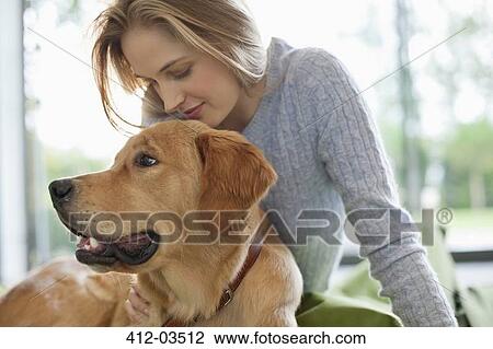 Stock Image - Woman relaxing with dog indoors. Fotosearch