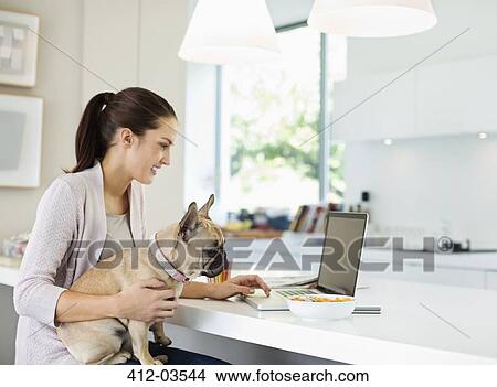 Picture - Woman using laptop with dog on lap. Fotosearch