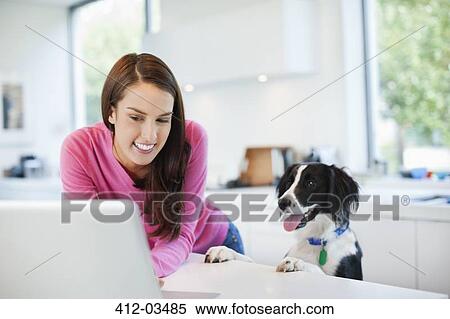 Woman using laptop with dog View Large Photo Image Stock Photography - Woman using laptop with dog. Fotosearch