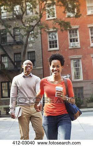 Couple walking together on city street View Large Photo Image Stock Image - Couple walking together on city street. Fotosearch