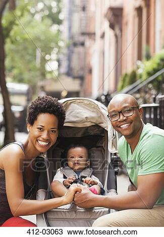 Stock Image - Family smiling together on city street. Fotosearch