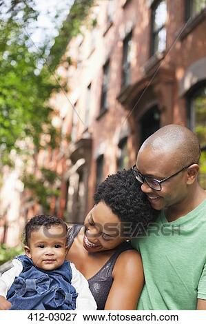 Stock Photo - Family smiling together on city street. Fotosearch