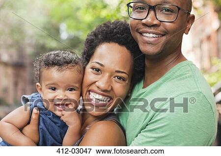 Stock Photo - Family smiling together on city street. Fotosearch