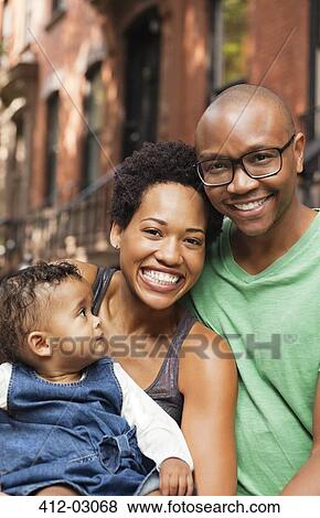 Stock Photo - Family smiling together on city street. Fotosearch