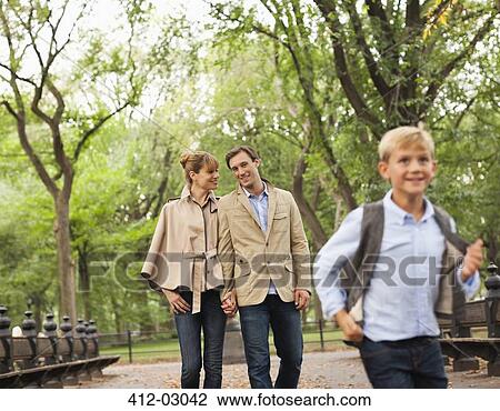 Stock Image - Family walking together in park. Fotosearch