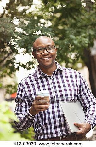 Stock Photo - Man carrying laptop on city street. Fotosearch