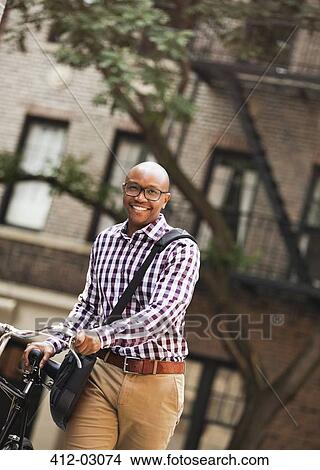 Man pushing bicycle on city street View Large Photo Image Picture - Man pushing bicycle on city street. Fotosearch
