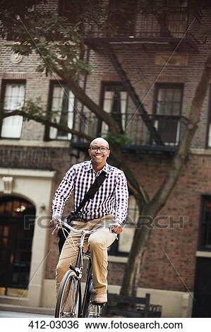 Man riding bicycle on city street View Large Photo Image Stock Photograph - Man riding bicycle on city street. Fotosearch