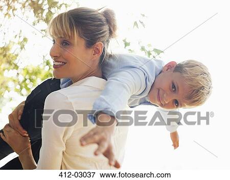 Stock Photo - Mother carrying son on shoulders outdoors. Fotosearch