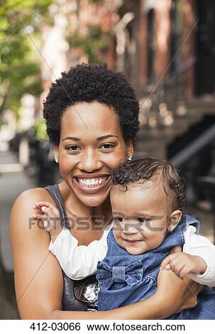 Mother holding baby on city street View Large Photo Image Stock Photograph - Mother holding baby on city street. Fotosearch
