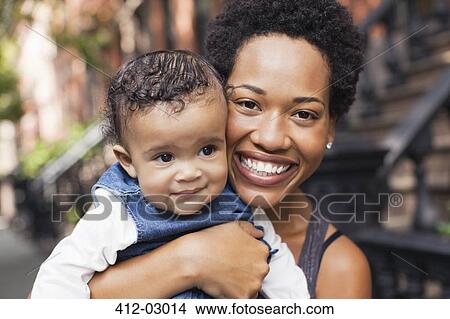 Mother holding child on city street View Large Photo Image Picture - Mother holding child on city street. Fotosearch