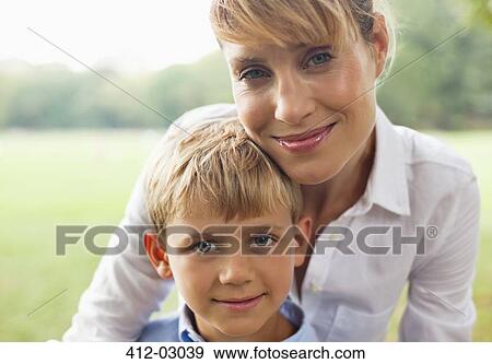 Stock Photo - Smiling mother hugging son outdoors. Fotosearch