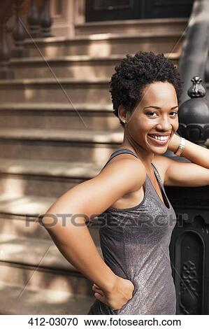 Stock Image - Smiling woman standing on city street. Fotosearch