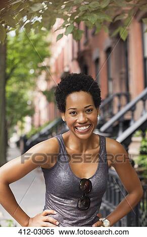 Smiling woman standing on city street View Large Photo Image Stock Photography - Smiling woman standing on city street. Fotosearch