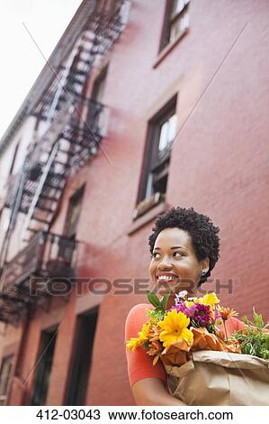 Woman carrying bag of flowers on city street View Large Photo Image Stock Image - Woman carrying bag of flowers on city street. Fotosearch