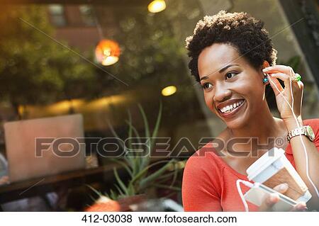 Woman listening to earphones on city street View Large Photo Image Stock Photo - Woman listening to earphones on city street. Fotosearch