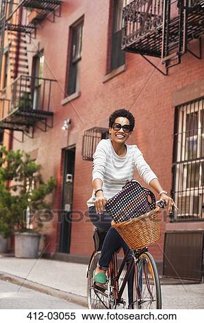 Stock Photography - Woman riding bicycle on city street. Fotosearch