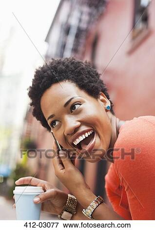 Stock Photo - Woman talking on cell phone on city street. Fotosearch