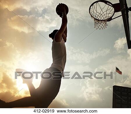 Man dunking basketball on court View Large Photo Image Stock Photo - Man dunking basketball on court. Fotosearch