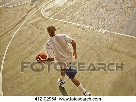 Picture - Man playing basketball on court. Fotosearch