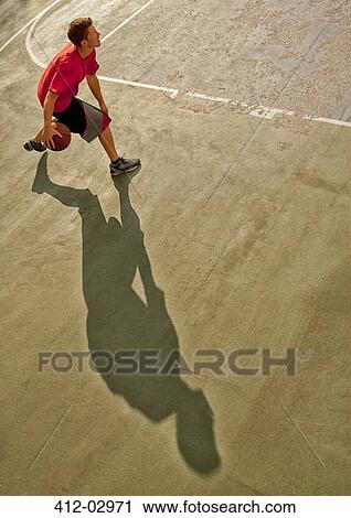 Stock Image - Man playing basketball on court. Fotosearch