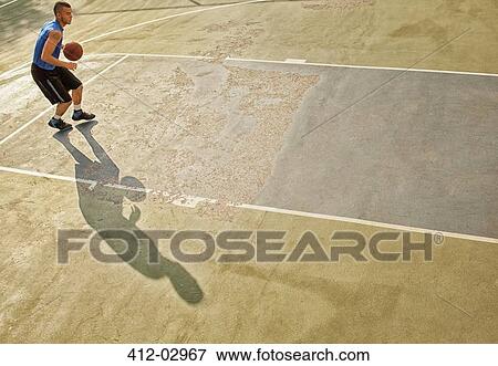 Stock Photo - Man playing basketball on court. Fotosearch