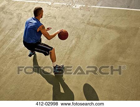 Stock Photo - Man playing basketball on court. Fotosearch
