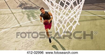 Stock Photograph - Man playing basketball on court. Fotosearch