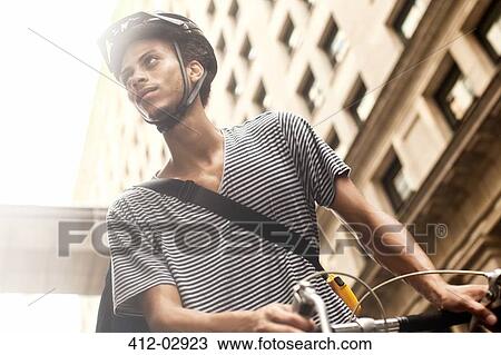 Man riding bicycle on city street View Large Photo Image Stock Image - Man riding bicycle on city street. Fotosearch