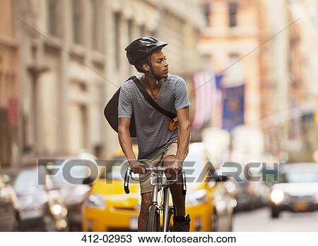 Stock Image - Man riding bicycle on city street. Fotosearch