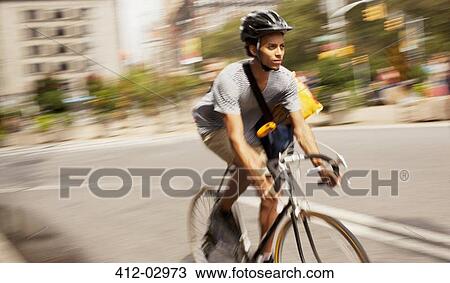 Stock Image - Man riding bicycle on city street. Fotosearch