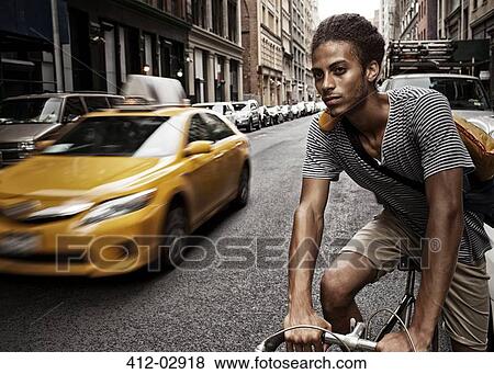 Stock Photo - Man riding bicycle on city street. Fotosearch
