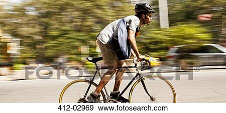 Stock Photo - Man riding bicycle on city street. Fotosearch