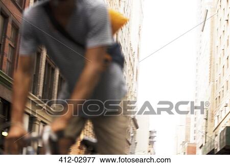 Stock Photo - Man riding bicycle on city street. Fotosearch