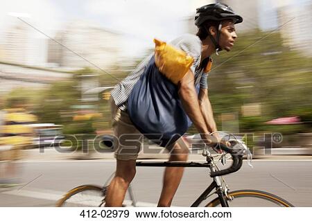 Stock Photo - Man riding bicycle on city street. Fotosearch