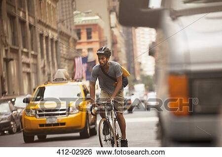 Stock Photograph - Man riding bicycle on city street. Fotosearch
