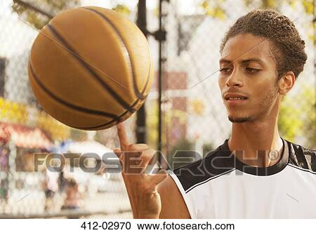 Stock Image - Man spinning basketball on finger. Fotosearch