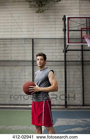 Stock Image - Man standing on basketball court. Fotosearch