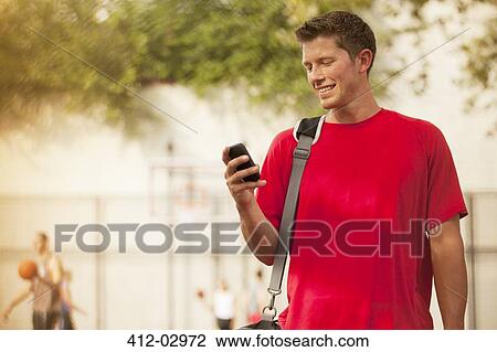 Man using cell phone on basketball court View Large Photo Image Stock Image - Man using cell phone on basketball court. Fotosearch